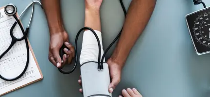 Top-down view of doctor's hands checking a patient's blood pressure